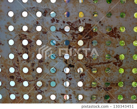 Perforated Metal Wall Showcasing Texture, Rust, and Reflections From a Vibrant Environment 130343451
