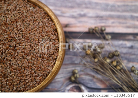 Flax seeds. Flaxseed powder in a wooden spoon. Standing on a Wooden background. 130343517