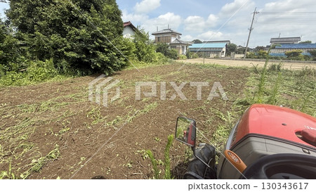 Shooting from the driver's seat of a tractor, plowing a field of grass 130343617