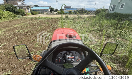 Shooting from the driver's seat of a tractor, plowing a field of grass 130343619