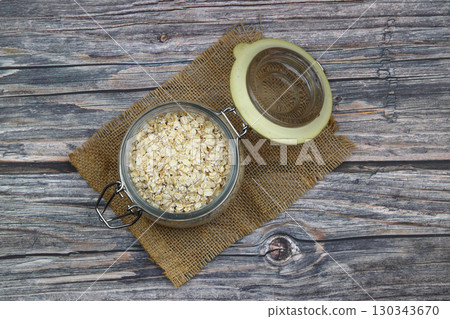 Oat flakes uncooked in a brown bowl on wooden table. Healthy food for breakfast Oat flakes uncooked in a brown bowl on wooden table. Healthy food for breakfast 130343670