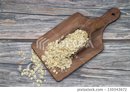 Oat flakes uncooked in a brown bowl on wooden table. Healthy food for breakfast 130343672