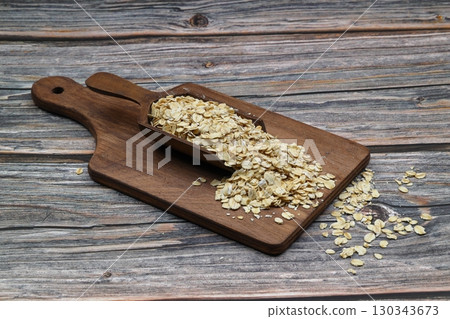 Oat flakes uncooked in a brown bowl on wooden table. Healthy food for breakfast Oat flakes uncooked in a brown bowl on wooden table. Healthy food for breakfast 130343673