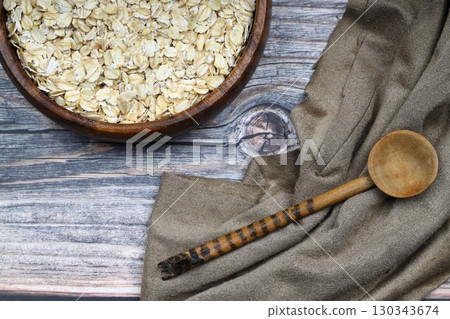 Oat flakes uncooked in a brown bowl on wooden table. Healthy food for breakfast 130343674