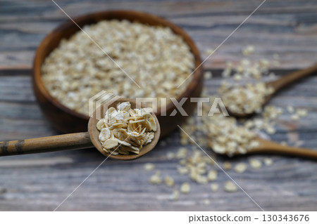 Breakfast cereals in wooden spoon. Healthy muesli with oat flakes, nuts and raisins isolated on wooden background. Selective Focus. 130343676