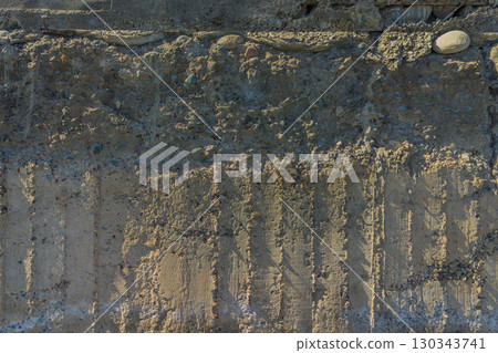 Weathered Cheap Uneven Concrete Surface with Pebbles under tangential harsh light 130343741