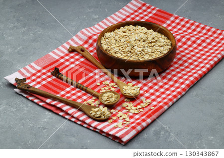 Oat flakes uncooked in a brown bowl on wooden table. Healthy food for breakfast 130343867