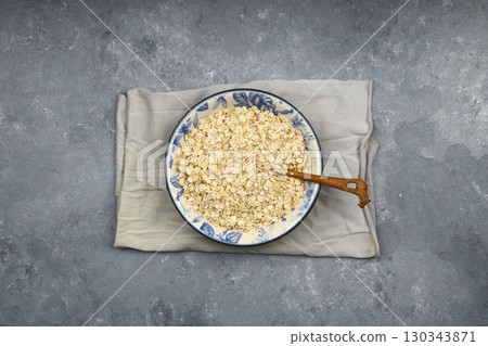 Oat flakes uncooked in a brown bowl on wooden table. Healthy food for breakfast 130343871
