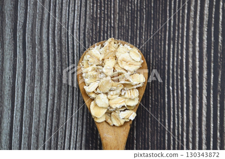 Breakfast cereals in wooden spoon. Healthy muesli with oat flakes, nuts and raisins isolated on wooden background. Breakfast cereals in wooden spoon. Healthy muesli with oat flakes, nuts and raisins isolated on wooden background. 130343872