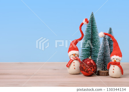 Christmas background with knitted snowmen in red hats and Christmas trees with red ball and space for text, greetings, promotions, and discounts. Christmas and New Year card. 130344134