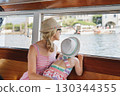Mother and daughter look out at Lake Maggiore through a window and sail to Isola Bella 130344355
