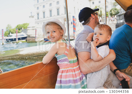 Father and children on a boat on Lake Maggiore sailing to the island of Isola Bella Father and children on a boat on Lake Maggiore sailing to the island of Isola Bella 130344356