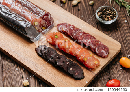Assorted gourmet sausages sliced and vacuum packed on rustic wooden background with spices 130344360