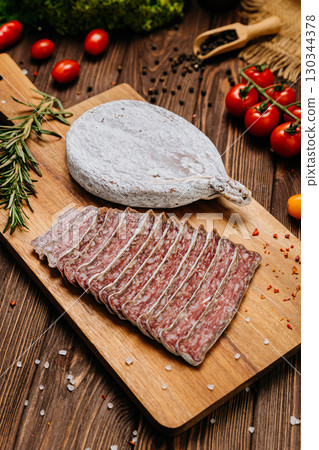 Traditional dry cured sausage slices on board with spices and herbs, perfect for food photography 130344378