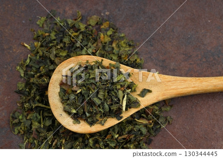 Green tea with herbs in wooden spoons on a wooden board 130344445
