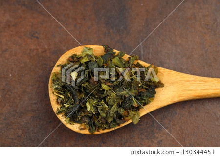 Green tea with herbs in wooden spoons on a wooden board 130344451