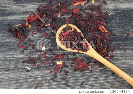 Karkade tea. Hibiscus tea leaves in wooden spoon isolated on wooden background. File contains clipping path. Top view. Selective focus. Karkade tea. Hibiscus tea leaves in wooden spoon isolated on wooden background. File contains clipping path. Top view. Selective focus. 130344524