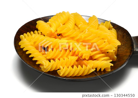 Raw pasta fusilli on wooden spoon on White background. Top view of Italian cuisine ingredient. Raw pasta fusilli on wooden spoon on White background. Top view of Italian cuisine ingredient. 130344550