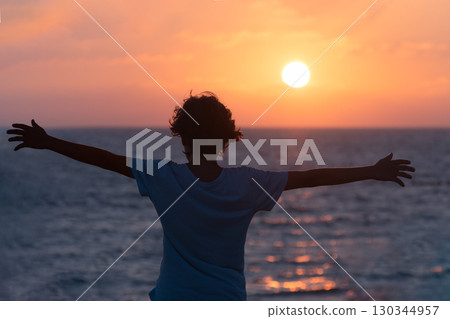 Person with Arms Stretched Out at a Sunset 130344957