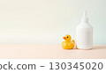baby yellow rubber duck toy and white lotion bottle on subtle background 130345020