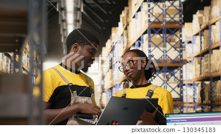 Black workers team preparing merchandise for dispatch in large warehouse, checking inventory on gadgets and managing cargo distribution. Sorting packages for orders logistics. Camera B. Black workers team preparing merchandise for dispatch in large warehouse, checking inventory on gadgets and managing cargo distribution. Sorting packages for orders logistics. Camera B. 130345183