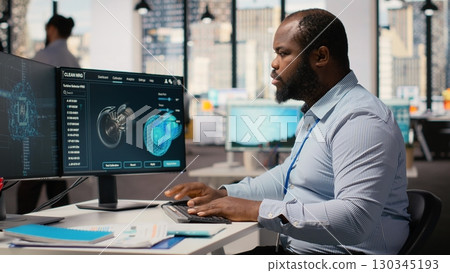 Engineer working on wind turbine simulation in office using artificial intelligence. RD department worker using AI tech and CAD program, doing renewable energy generation engineering, camera B Engineer working on wind turbine simulation in office using artificial intelligence. RD department worker using AI tech and CAD program, doing renewable energy generation engineering, camera B 130345193
