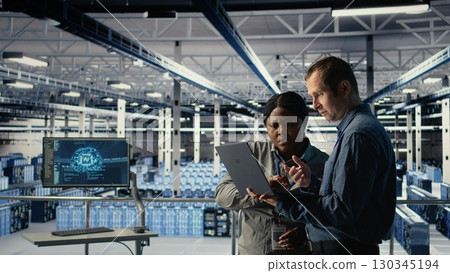Team of engineers in server hub optimizing deep learning AI systems handling tasks. Teamworking data center colleagues adjust artificial intelligence model parameters using device, camera A Team of engineers in server hub optimizing deep learning AI systems handling tasks. Teamworking data center colleagues adjust artificial intelligence model parameters using device, camera A 130345194