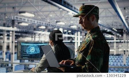 Military soldier and engineer in server room use AI tools to manage computer systems. Army commander and female programmer review information using artificial intelligence in server farm, camera B Military soldier and engineer in server room use AI tools to manage computer systems. Army commander and female programmer review information using artificial intelligence in server farm, camera B 130345229