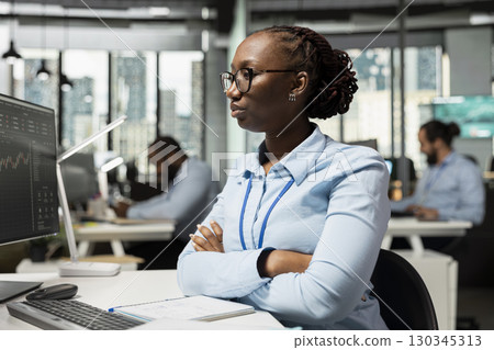 Brokerage company expert in office at workstation desk analyzing stock market charts. African american woman looking at PC financial software interface in prop firm workspace Brokerage company expert in office at workstation desk analyzing stock market charts. African american woman looking at PC financial software interface in prop firm workspace 130345313