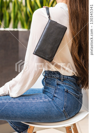 Girl holds dark purse over her shoulder 130345341