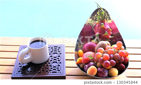 Vibrant tropical fruits scattered in ceramic bowl near steaming coffee mug, poolside setting capturing leisurely summer morning relaxation Vibrant tropical fruits scattered in ceramic bowl near steaming coffee mug, poolside setting capturing leisurely summer morning relaxation 130345844