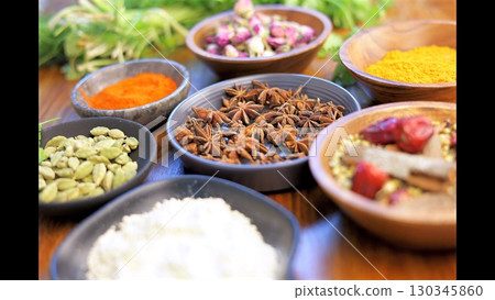 Rustic wooden surface displaying colorful spices and herbs in small ceramic bowls, representing culinary diversity and aromatic potential Rustic wooden surface displaying colorful spices and herbs in small ceramic bowls, representing culinary diversity and aromatic potential 130345860