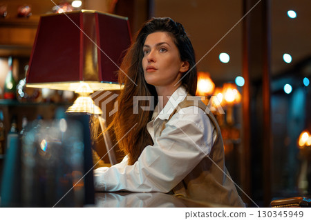 Thoughtful woman sitting at bar counter under warm Thoughtful woman sitting at bar counter under warm 130345949