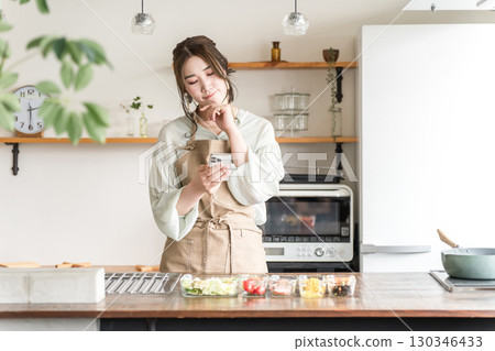 在家庭廚房/餐廳使用智能手機應用程序的亞洲女性 130346433