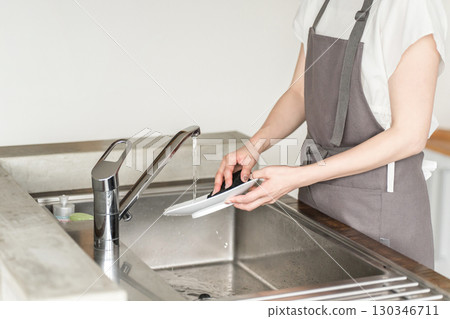 Hands of a housewife washing dishes in the kitchen sink Hands of a housewife washing dishes in the kitchen sink 130346711