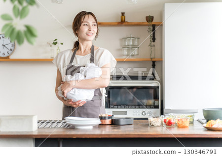 年輕的亞洲婦女在廚房裡抱著孩子 130346791