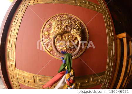 The ancient Tibet styles door handle or door knocker made from brass on red door. 130346951