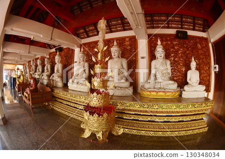 Row of indoor sitting white Buddha statue decoration in cloister at Wat Den Sali Si Mueang Kaen temple or Wat Ban Den. Located at Chiang Mai Province in Thailand. 130348034
