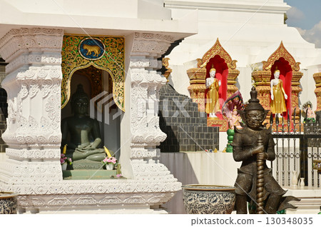 Stone Buddha statues in niches and outdoor standing Buddha statues and giants in front of the 12 Zodiac pagodas at Wat Den Salisri Mueang Kaen temple. 130348035