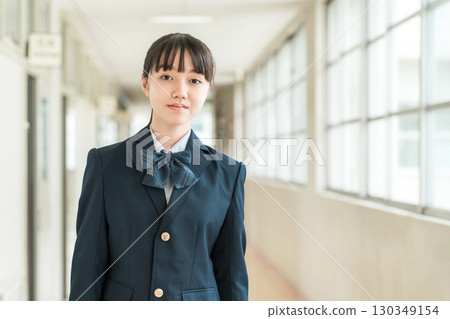 Female students, elementary school students, junior high school students, and high school students in uniform walking down a school corridor 130349154