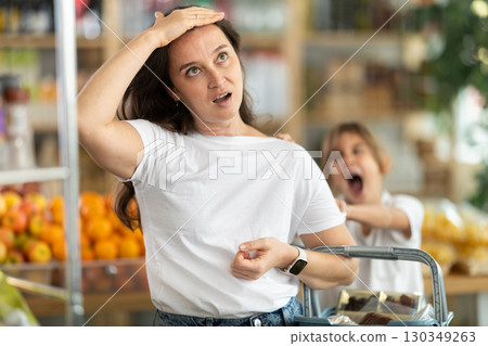 Tired and angry mother with basket of groceries in her hands quarreling with her little daughter. 130349263