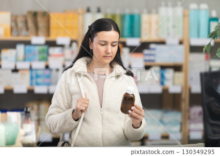 Woman choosing cough syrup at pharmacy Woman choosing cough syrup at pharmacy 130349295