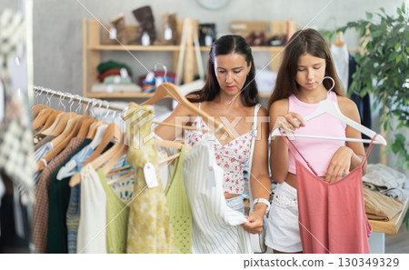 Near rack, mom with daughter buys summer dress, chooses items. Near rack, mom with daughter buys summer dress, chooses items. 130349329