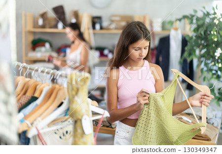 Teenage girl choosing something for summer in clothing store Teenage girl choosing something for summer in clothing store 130349347