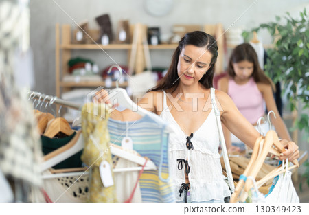 Middle-aged woman choosing something for summer in clothing store 130349423