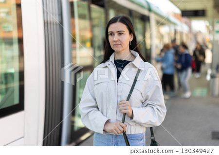 Woman is waiting for tram at stop of urban transport with spring day 130349427