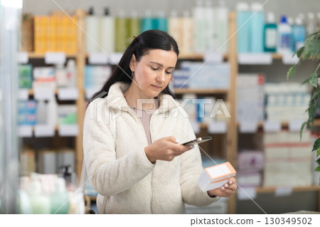 Woman in pharmacy scans QR code on antiallergic pills box product Woman in pharmacy scans QR code on antiallergic pills box product 130349502
