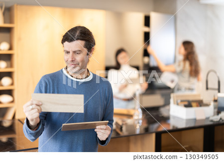 Man standing in furniture salon with examples of wood Man standing in furniture salon with examples of wood 130349505