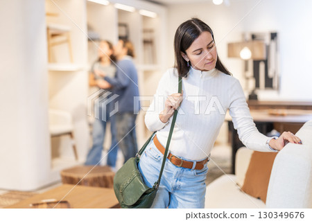 Woman looking at the upholstery on the sofa Woman looking at the upholstery on the sofa 130349676