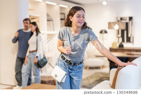 Woman looking at the upholstery of a sofa in a store 130349686
